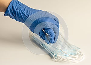 A hand in a protective rubber glove takes a medical mask.Concept of protection against viruses and infections