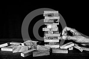 Hand pull wooden block tower stack in pyramid stair step with caution to prevent collapse or crash concepts of financial risk