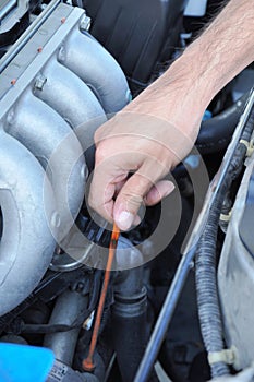 Hand pulling dipstick checking car engine oil