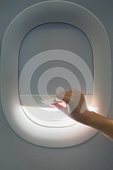 Hand pulling down aircraft window curtain