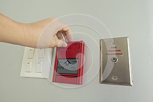 The hand is pulling fire alarm signal on the wall