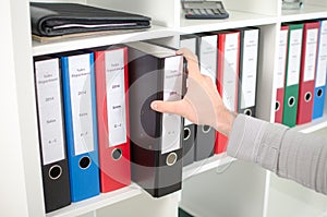 Hand pulling out a folder from a shelf