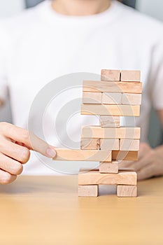 hand pulling wooden block tower on table. Business planning, Risk Management, Solution, leader, strategy, Crisis, falling Business