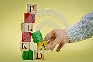 A hand pulling a wooden element from a collapsing tower built of blocks with the inscription Polski ÃÂad Polish language Concept photo