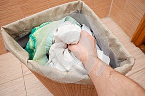 Hand pulls dirty clothes out of the laundry basket