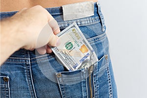 a hand pulls dollar bills out of the pocket of someone else's jeans. The concept of theft