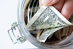 Hand pulls one dollar banknote in glass jar