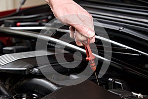 Hand pulls out oil dipstick in a clean car engine bay