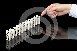 Hand pushing dominoes counters on black photo