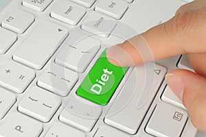 Hand pushing green diet keyboard button