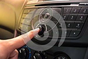 Hand Pushing the power button to turn on the car stereo