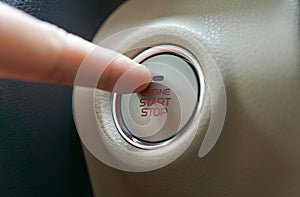 Hand pushing a push start button of a car