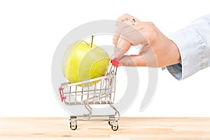 Hand pushing red shopping cart trolley with green apple isolated on white background. Shopping concept.