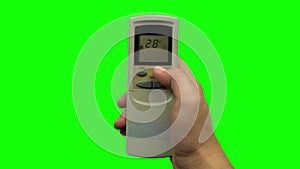 Hand pushing temperature button on air conditioner remote control. Green screen