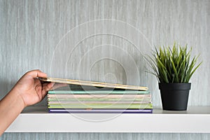 Hand put book on white shelf - get organized