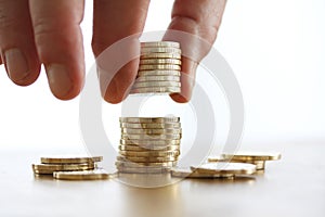 Hand put coin to money stack on white background. Close-up of hand putting a coin to stack of coins. Business finance and money