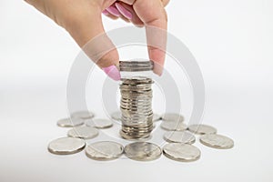 Hand put coins to stack of coins on white