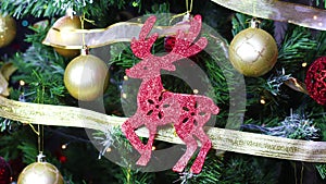 Hand put glitter red reindeer ornament on Christmas tree