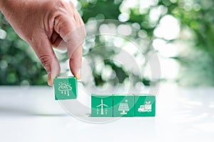 Hand put green wooden cubes with net zero icon and white icon on bokeh nature. Net zero and carbon neutral concept. Net zero