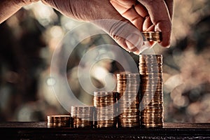 Hand put growing coins stacks with bokeh background in vintage t