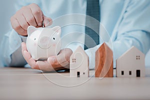 Hand put money coin into piggy bank for saving money wealth. business people working at desk with piggy bank box.business finance