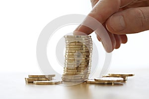 Hand put more gold coins to money stack on white background. Close-up of hand putting a coin to stack of coins. Business finance a