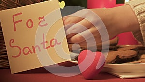 Hand put note For Santa near gingerbread cookies and toy heart, gift with love