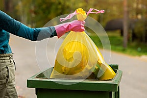 hand put plastic unsorted garbage bag into trash bin. household waste