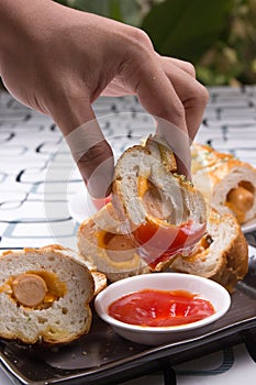 Hand put sausage bread with ketchup and cola drink photo