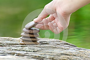 Hand put stone building a pile of zen stones