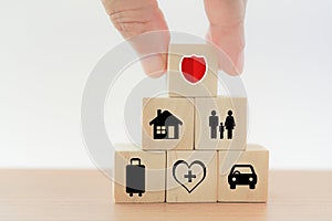 Hand put wooden block with security on top of pyramid shape on wood table for property, personal, family, travel and health