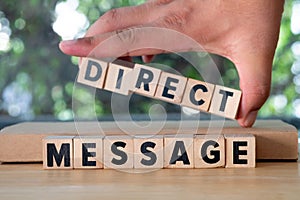 Hand put of word from wooden blocks with letters `Direct Message`