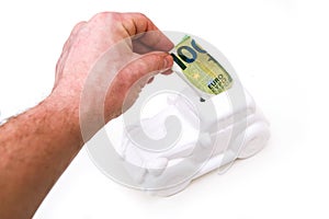 The hand is puting a banknote into the ceramic car shaped money box