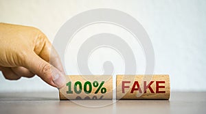 Hand puts blocks with the words 100% fake. Fake news and false information, misleading. Misinformation. Business concept