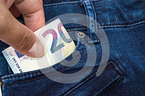 The hand that puts  20 euro banknotes in a pocket of jeans photo