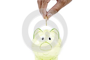 Hand puts golden coins in the transparent piggy bank