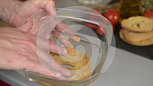 hand puts one frisa tipical apulian dish in water to moisten before being eaten