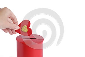 hand puts Red heart into slot of red donation box. Concept of donorship, life saving or charity.