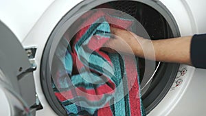 Hand puts towel inside steel washing machine drum