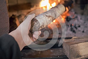 a hand puts a wood into a stove, indoor close up