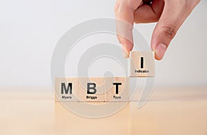 Hand puts wooden cubes with MBTI, Myers-Briggs Type Indicator on table