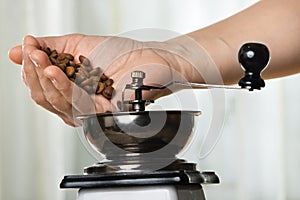 Hand putting coffee beans to grinder