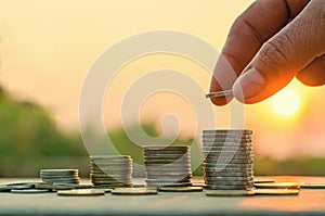 Hand putting coin on coins stack