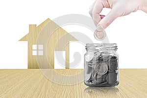 Hand putting coin into glass container of buying a new house - saving money for future concept