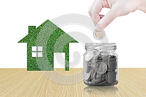 Hand putting coin into glass container of buying a new house - saving money for future concept