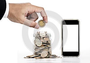 Hand putting coin and glass jar full of coins with mobile phone, isolated screen for copy space