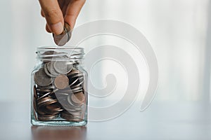 Hand putting coin in glass jar for save money for prepare in the future