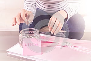 Hand putting a coin into glass jars with 'wedding' text