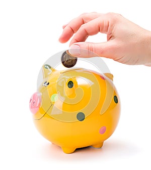 Hand putting a coin into piggy-bank