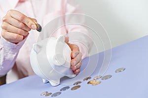 Hand putting coin into piggy bank closeup. Selective focus